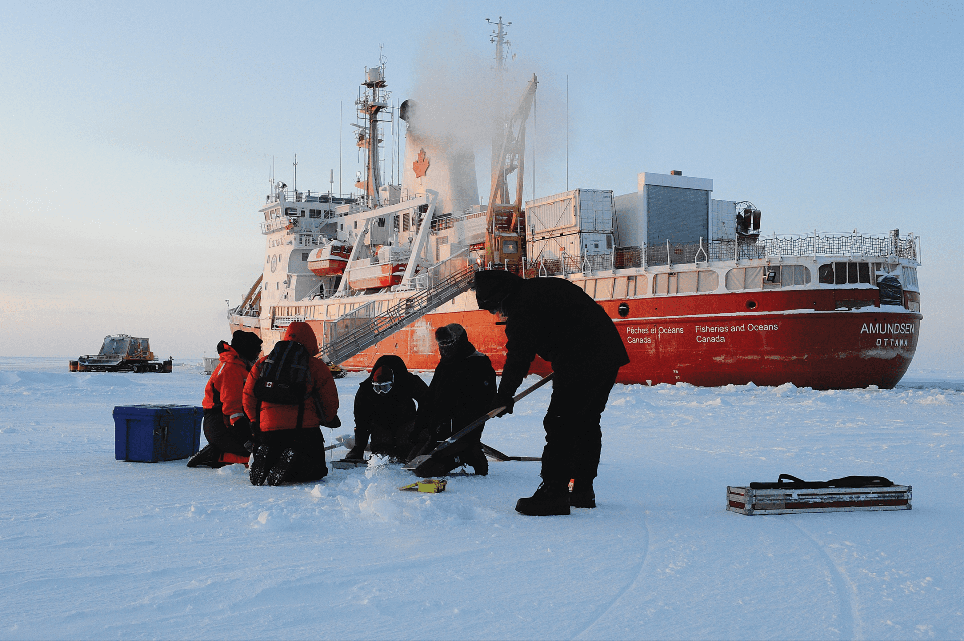 Workers on the snow with icebreaker CCGS Amundsen in the background